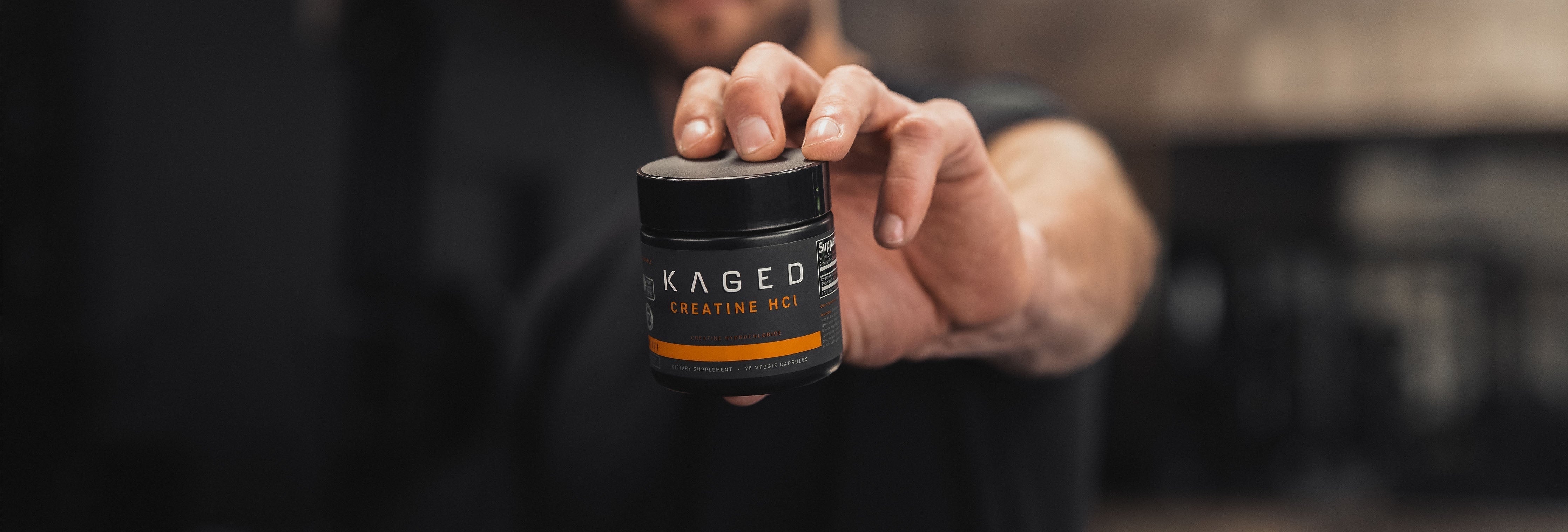 Male Kaged athlete holding a bottle of Creatine HCl