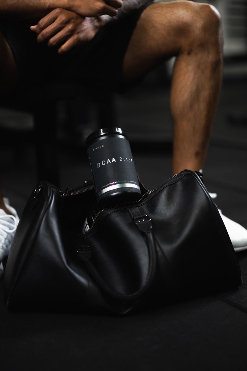 Angled view of BCAA 2:1:1 supplement tub showcasing matte black packaging in an open gym bag on a gym floor