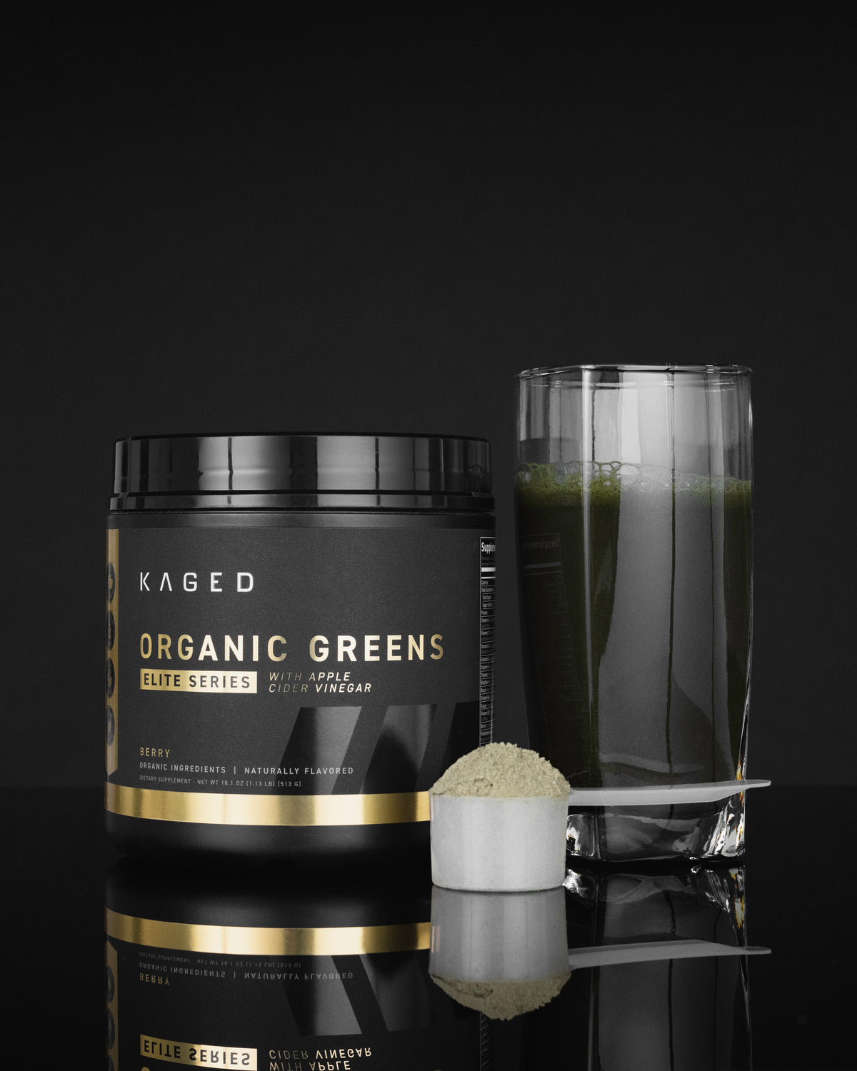Front view of Kaged Organic Greens Elite powder tub with a glass of mixed green drink and a scoop on a black background