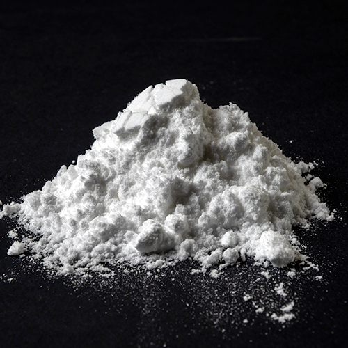 Close-up of Creatine HCl powder mound showcasing fine white powder texture on black background