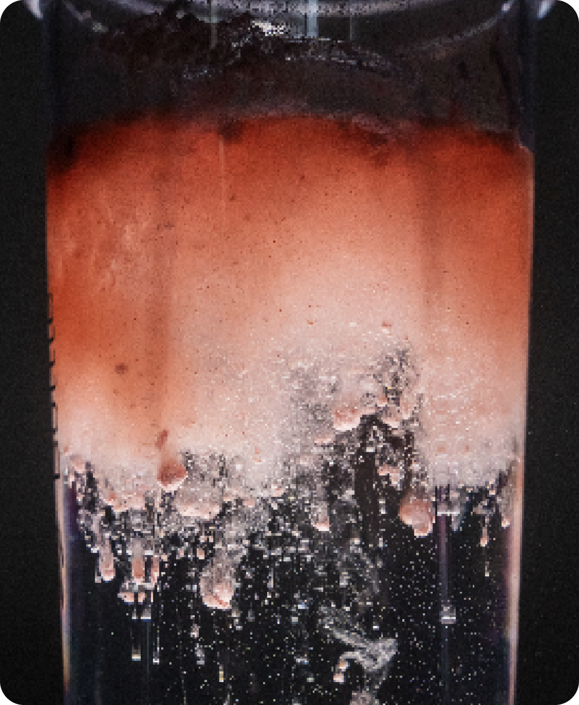 Close-up of Pre-Kaged Stim-Free pre-workout dissolving in water, showing pink-orange clouding and fizz against black